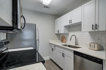 A kitchen with white cabinets and a black stove top.at Eastlake Gardens, Georgia, 30032
